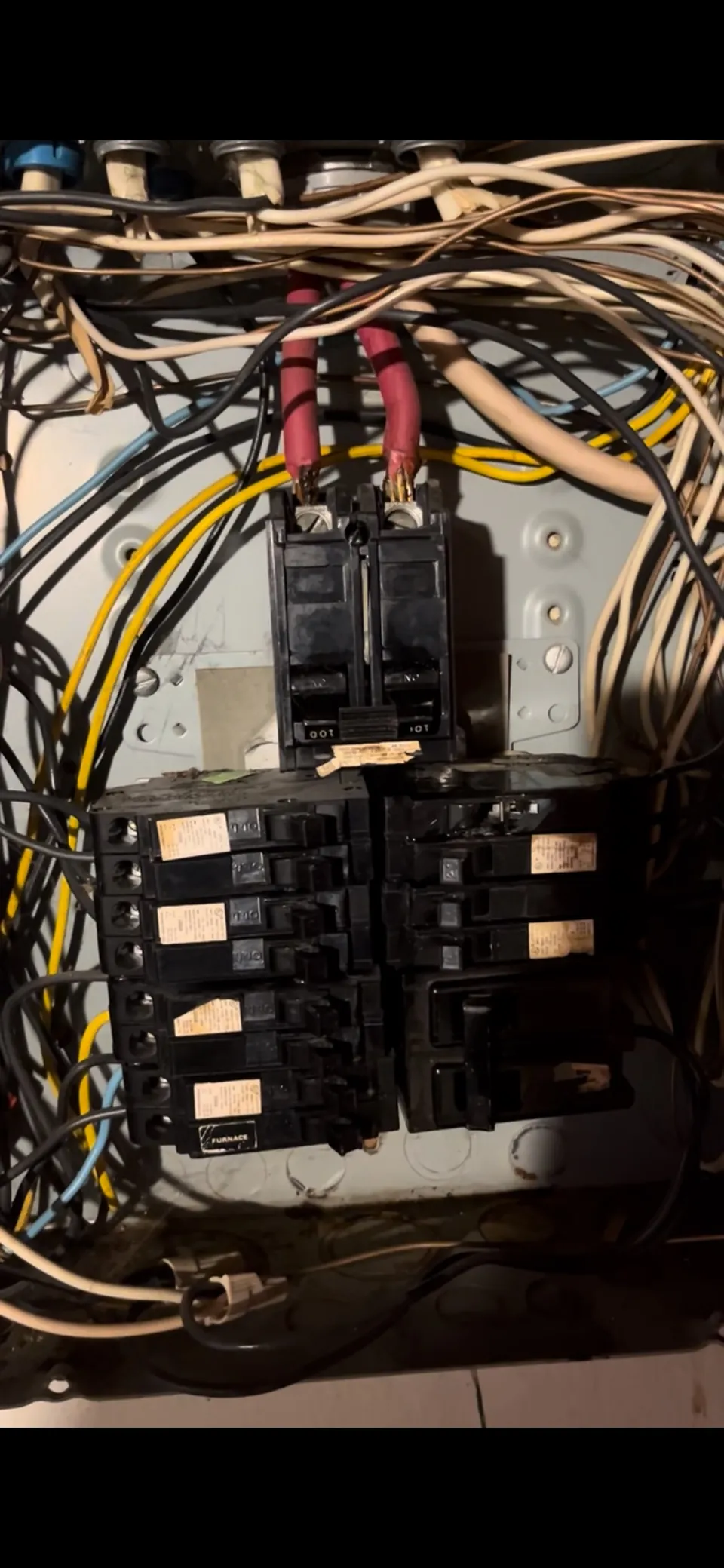 Close-up of an older electrical panel with two wires landed under one breaker terminal